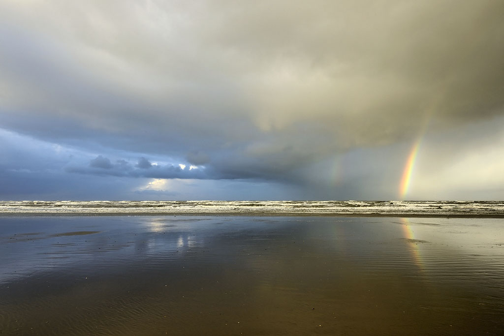 Regenboog aan de onderkant van een dreigende hagelbui boven zee op het Kennemerstrand bij IJmuiden;Rainbow at the bottom of a big hailstorm over the sea at the Kennemer beach at IJmuiden