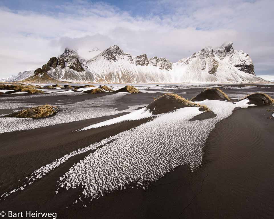 Het gemarmerde patroon van sneeuw en zand neemt de kijker mee het beeld in. De duintoppen fungeren als accenten en laten het oog rondspringen.